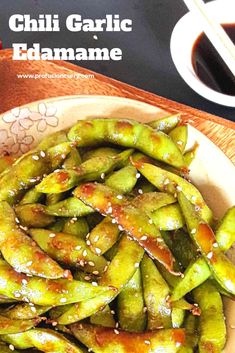 grilled green beans with chili garlic and sesame seeds in a bowl next to chopsticks