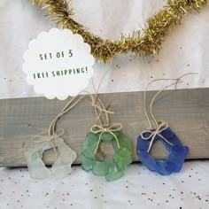 three pieces of glass sitting on top of a piece of wood next to a christmas tree