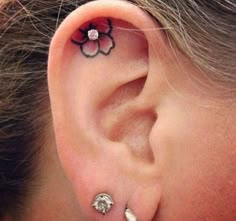 a woman's ear has a flower tattoo on it