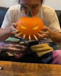 a man sitting on a couch with a pumpkin in his hands and nails sticking out from it