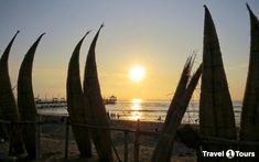 the sun is setting over the beach with palm trees in front of it and people on the water