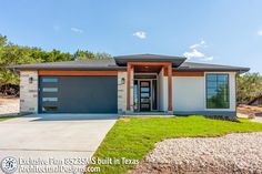 a house that is in the middle of some grass and dirt with two garages