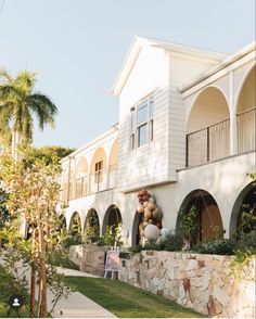 a large white building with arches and balconies on the front, surrounded by palm trees