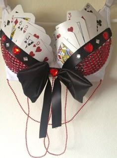 a bra made out of playing cards hanging on a wall with chains and beads attached to it