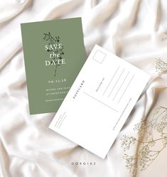 save the date postcard on top of a white sheet with greenery in it