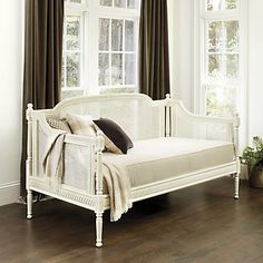 a white day bed sitting in front of a window