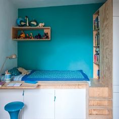 a bedroom with blue walls and shelves on the wall, along with a small bed