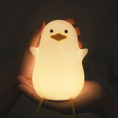 a person holding a lit up penguin in their hand with the light shining on it