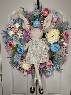 a wreath with a bunny doll hanging on the front door