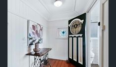 an entryway with a clock on the wall and wooden flooring in front of it