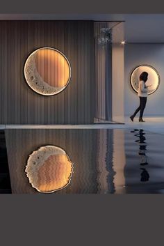 a woman standing in front of a wall with two circular mirrors on it's side