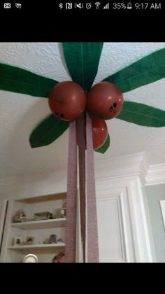 the ceiling fan is decorated with red balls and green leafy leaves on it's blades