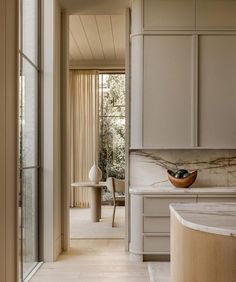 a kitchen with white cabinets and marble counter tops in front of a sliding glass door