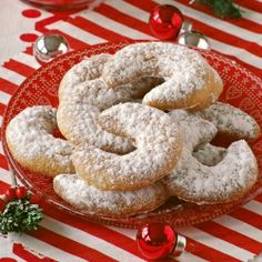 a plate full of powdered sugar donuts on a red and white tablecloth