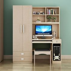 a computer desk with a monitor on top of it in front of a bookcase