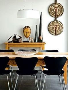 a dining room table with chairs around it and artwork on the wall in the background