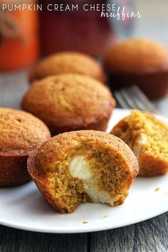 several muffins on a white plate next to a jar of pumpkin cream cheese