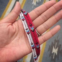 a hand holding a red, white and blue bracelet