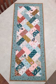 a blue and pink patchwork quilt on the floor