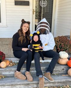 two women and a baby are sitting on the steps in front of a house decorated for halloween