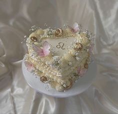 a heart shaped cake with flowers and butterflies on it sitting on a white platter