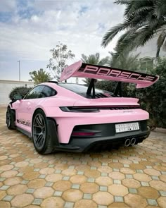 a pink sports car parked in front of a palm tree