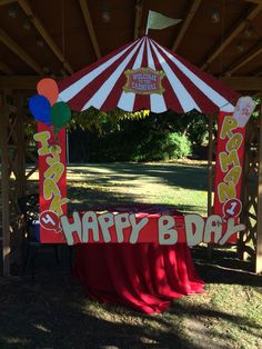 a red and white circus tent with happy bday sign on the table under it