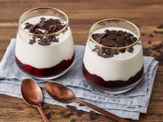 two desserts with chocolate chips and raspberry sauce in glass bowls on a wooden table