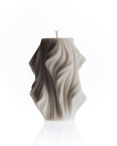 a candle that is sitting in the middle of a white tablecloth with waves on it