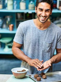 a man standing in front of a metal tray with food on it and smiling at the camera