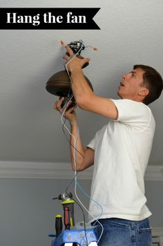 a man working on a ceiling fan with the words hang the fan above his head