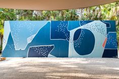 a large blue painting on the side of a building with trees in the back ground