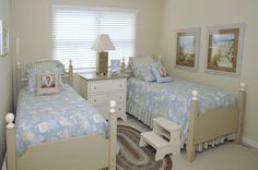 two twin beds in a bedroom with blue and white bedding, rugs and pictures on the wall