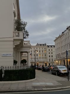 a white building on the corner of a street with cars parked in front of it