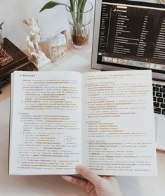 an open book sitting on top of a desk next to a laptop