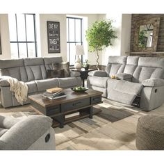 a living room with couches, chairs and a coffee table in front of windows