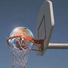 a basketball going through the rim of a hoop with a blue sky in the background