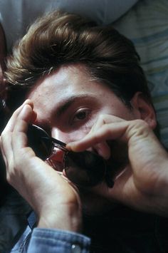 a man laying on top of a bed while holding onto a cell phone to his ear