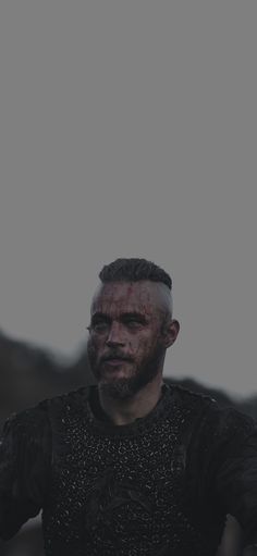 a man dressed in black with blood all over his face and arms, standing outside