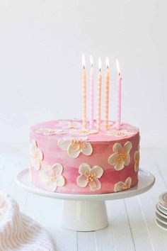 a cake with pink frosting and white flowers on it, sitting on a plate