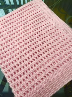 a pink crocheted blanket sitting on top of a chair