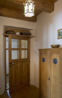 a wooden cabinet sitting in the corner of a room next to a door and window