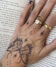 a woman's hand with a butterfly tattoo on it, and an open book