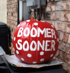 a painted pumpkin sitting on top of a piece of paper next to a brick wall