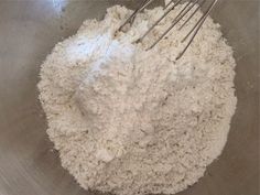 a mixing bowl filled with flour and whisks