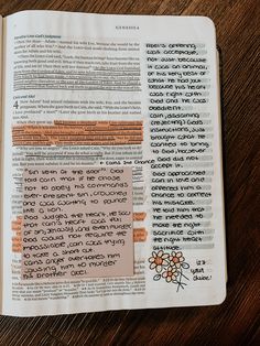 an open bible on a wooden table with orange and black writing in the center, surrounded by flowers