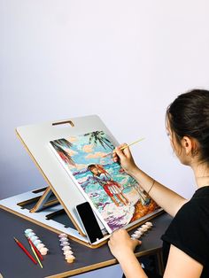 a woman is painting on an easel with pencils