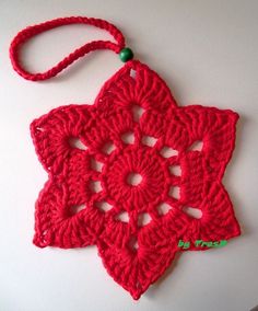 a red crocheted star ornament hanging from a hook on a wall