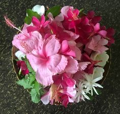 pink and white flowers in a bowl on the ground