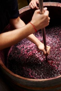 a person holding an umbrella over a barrel filled with liquid and cranberry sauce